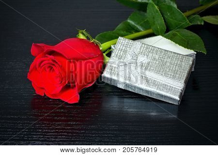 Red rose with gift. For lovers. Rose and gift. Romantic atmosphere. Valentine's day theme. Romantic moments.