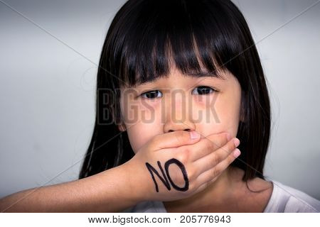 Child Covering her Mouth with 'No' Written Over the Hand
