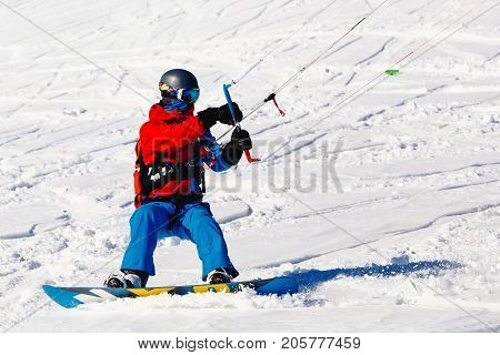 Snowboarder with a kite on fresh snow in the winter in the tundra of Russia against a clear blue sky. Teriberka, Kola Peninsula, Russia. Concept of winter sports snowkite.