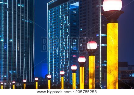 row of lighting street lamps with modern highrises on background,tianjin,china.