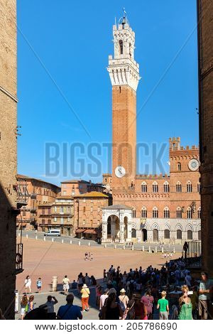 SIENA,ITALY - JULY 23,2017 : Tourists at Piazza del Campo next to the Palazzo Publico on the medieval city of Siena