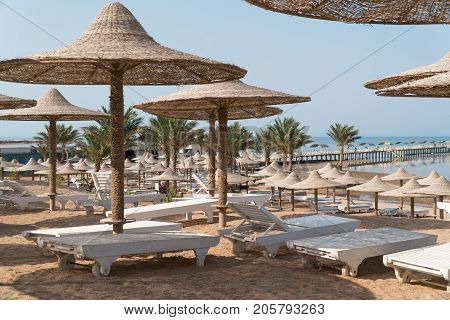 The beach with umbrellas and sun beds which are empty.