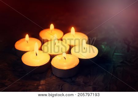 Burning Small Wax Candles On Dark Background.