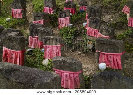 Nara - Japan, May 30, 2017: Peaceful stone relegious Jizo statues with red skirts in the garden