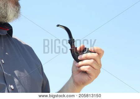 man smokes a handmade tube of cherry wood

