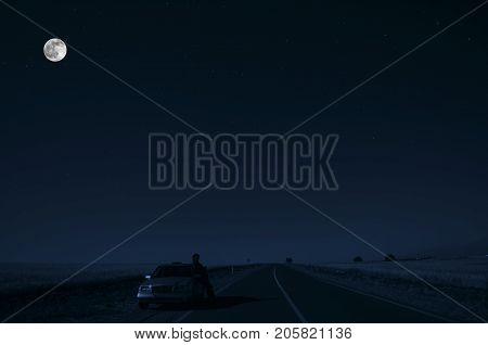 Road With Car And Sillhouette Of Man And A Car At The Road Side At Night Under Moon Light. Azerbaija