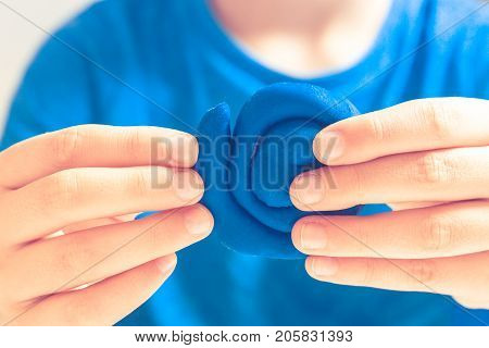Kids hands making toy figure with modeling clay or plasticine