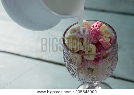 Close-up of milk being pour into glass of honeycomb cereal