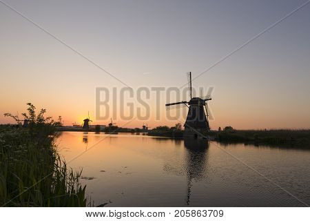 Travelling Concepts and Ideas. UNESCO Heritage Dutch Windmills In Front of The Canal and Sun at Kinderdijk Located in Traditional Village in Holland The Netherlands. Horizontal Shot