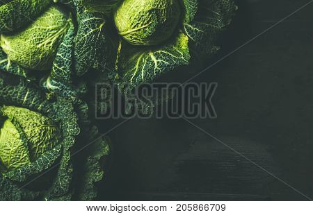 Raw fresh uncooked green cabbage over dark background, top view, selective focus, copy space