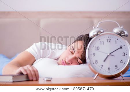 Man in bed frustrated suffering from insomnia with an alarm cloc