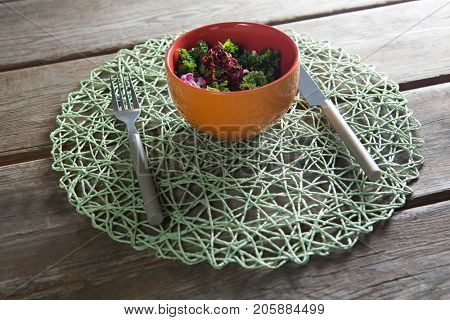 High angle view of vegetable salad in bowl on place mat at wooden table