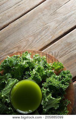 Close up overhead view of fresh kale juice in glass on wooden table