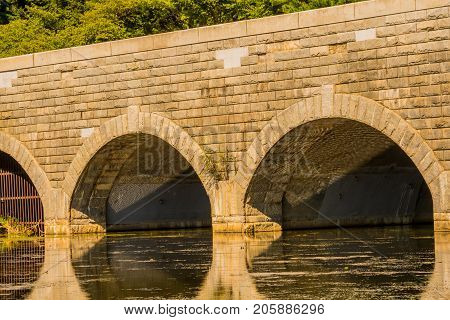 Closeup of large brick bridge with arched tunnels spanning a river