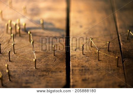 Connected. Overcoming divides and obstacles and linking separated people and groups. Networking, social media, internet communication abstract concept image. Web of gold wires on rustic wood. 