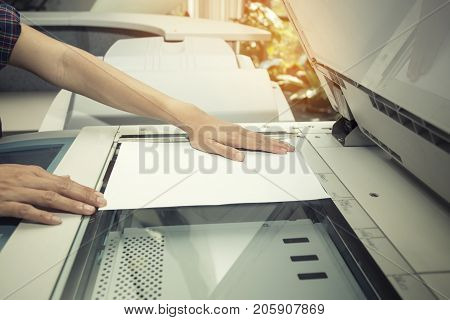 woman hands putting a sheet of paper into a copying device