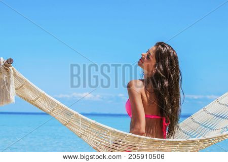Young woman swinging in hummock on blue sea background