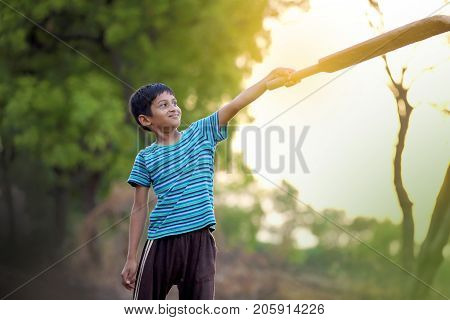 cute indian poor child playing cricket  at village