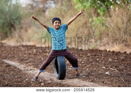 cute indian poor child playing cricket  at village
