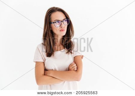 Serious brunette woman in eyeglasses with crossed arms looking away over white background