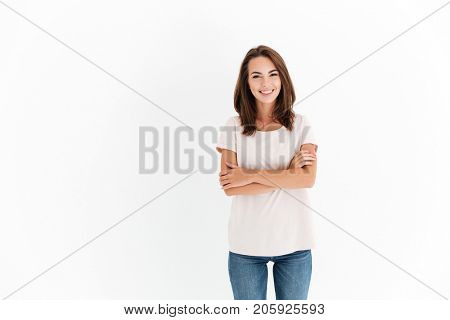 Smiling brunette woman with crossed arms looking at the camera over white background