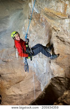 Speleologist performing rope maneuvers in a cave. Zaragoza Province, Aragon, Spain.