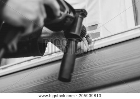 A worker installs panels beige siding on the facade of the house