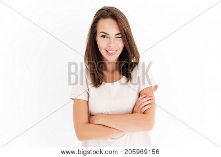 Carefree woman with crossed arms winks at the camera over white background