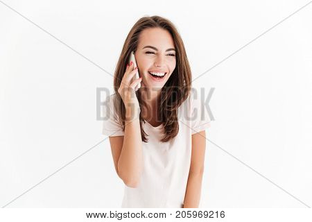 Pretty laughing woman talking by the smartphone and looking away over white background