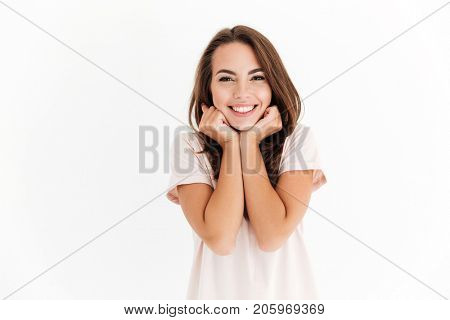 Pleased brunette woman reclines on her hands and looking at the camera over white background