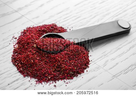 Maqui berry powder and measuring spoon on wooden background