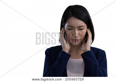 Businesswoman listening music on headphones against white background