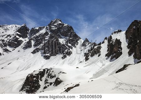 Snowy Sunlight Rocks With Traces From Avalanches And Slope With Footprints In Sunny Spring Day. Turk