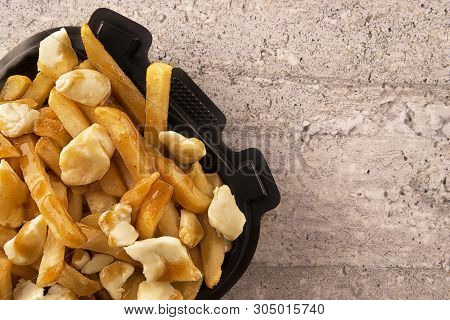 Poutine In A Takeout Container. Cooked With French Fries, Gravy And Curd Cheese. Canadian Cuisine.