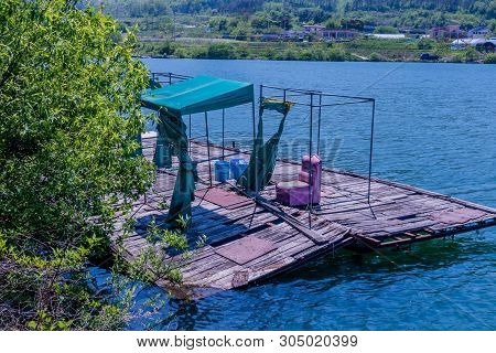 Metal Frame Fishing Shelters With Destroyed Fabric Coverings On Old Wooden Fishing Dock At Edge Of L