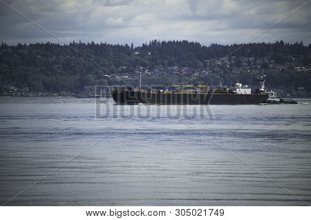 Tug Boat Guides Commercial Ship Off The Shore Of Point Robinson Park, Vashon Island.