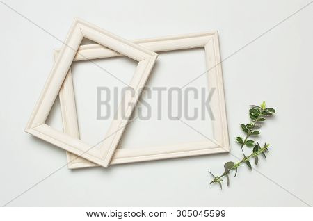 White Wooden Photo Frame And Spring Green Twigs Of Plants On Gray Background. Flat Lay Top View Copy