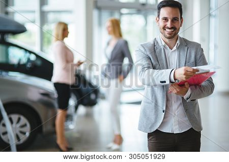 Handsome Salesman At Car Dealership Selling Vehichles