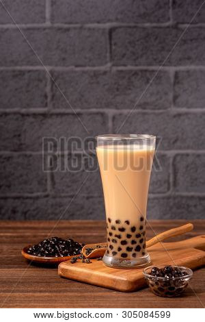 Delicious Bubble Milk Tea With Tapioca Pearl Ball In Glass On Wooden Table And Dark Gray Brick Backg