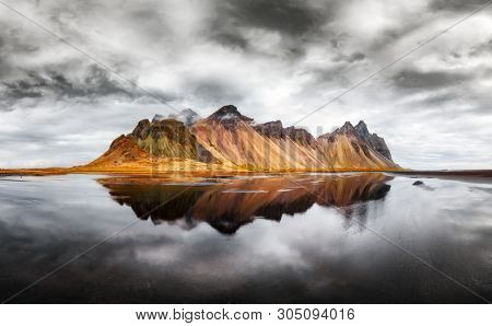 Incredible landscape of the famous Stokksnes mountains on Vestrahorn cape. Reflection in the clear water on the epic skies background, Iceland
