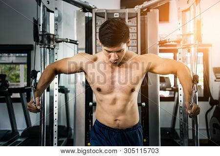 Athlete Muscular Bodybuilder Training On Simulator In The Gym, Strong Male.