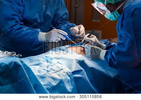 Surgery Team Operating In A Surgical Room.doctors Working Operation Against Dark Room Background.