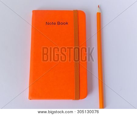 ..orange Notepad And Next To It Is An Orange Pencil On The Office Desk