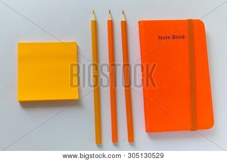 ..orange Notebook Lies On The Table Next To An Orange Pencil And Sticker