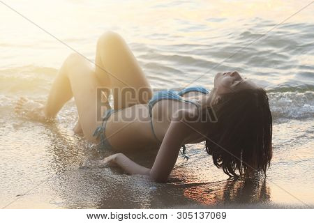 Sexy Woman In Bikini Is Relaxing Ans Sunbathing  On The Beach During Summer Time.