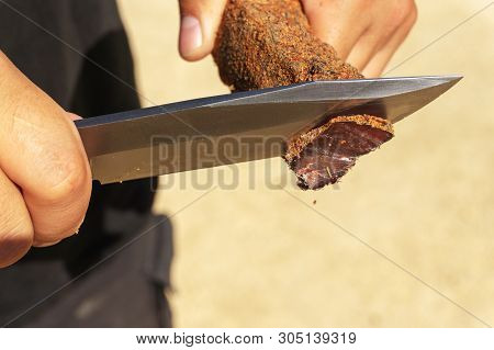 A Man Cuts A Basturma With A Large Knife. Close-up