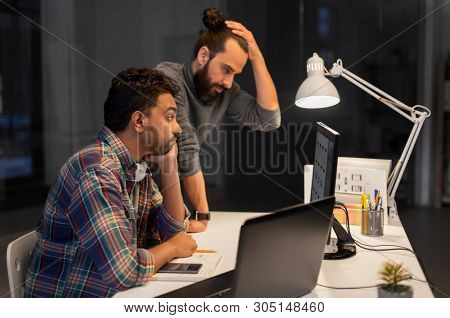 deadline, technology and people concept - creative team with computers working together late at night office