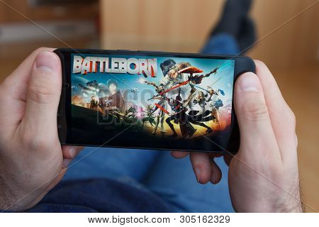 Los Angeles, California - June 3, 2019: Lying Man Holding A Smartphone And Playing The Battleborn Ga