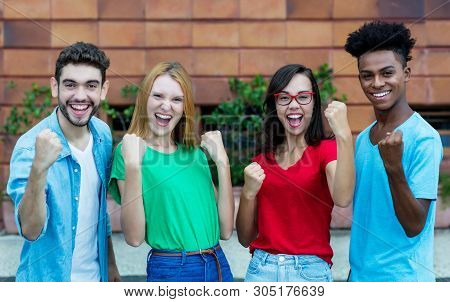 Cheering Group Of Four Young Adults Of Generation Y Showing Thumbs Outdoor In The Summer In The City