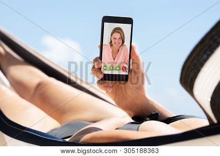 Woman Lying On Hammock Video Conferencing With Her Female Friend On Mobile Phone